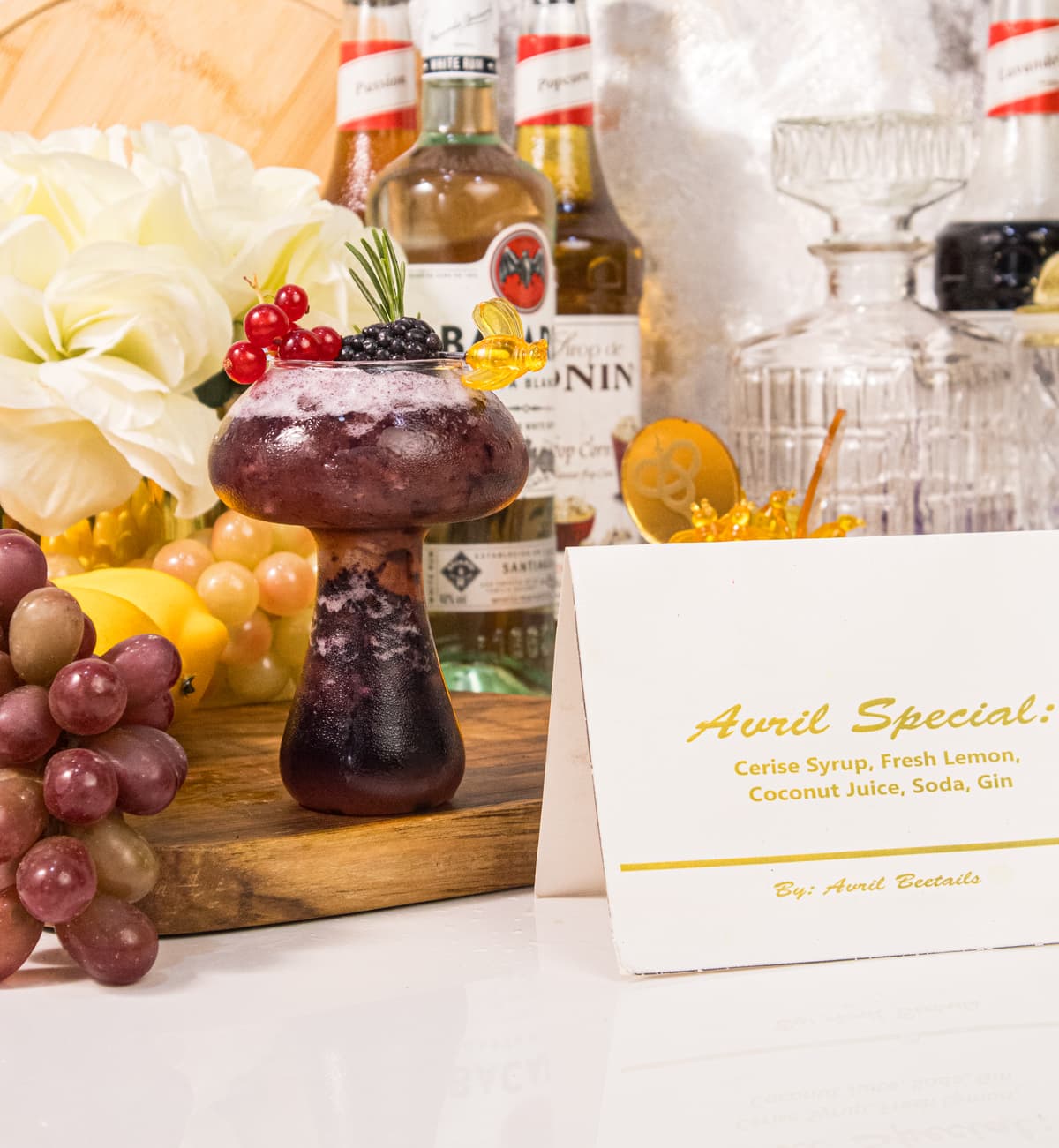 Our signature Avril Special — cerise syrup, fresh lemon, coconut juice, soda and gin, finished with a honeybee glass pin. The drink that carries our name.